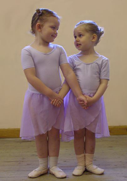 Two very young girls in purple outfits